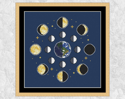 Moon Phases cross stitch pattern on dark fabric. Shown with frame.
