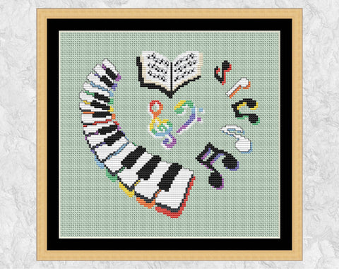 Piano Heart cross stitch pattern. Heart shape formed fromo a keyboard, music notes, music book and treble and bass clefs. Shown in frame.
