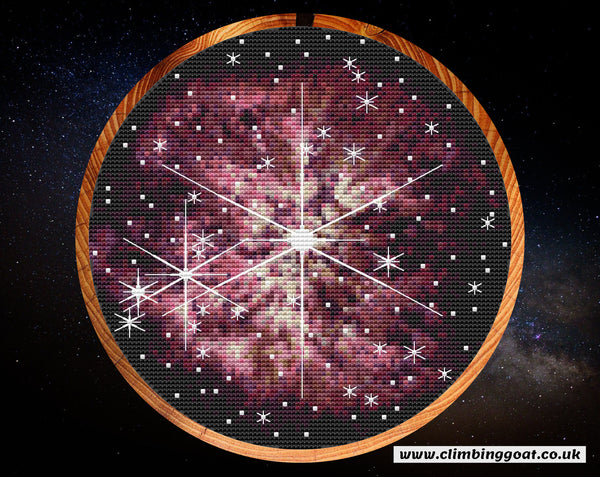 Wolf-Rayet 123 cross stitch pattern. A large star in the centre of the image is puffing off layers of pink gas and dust. Many other stars are in the picture. Some of the stars have large 8 line diffraction spikes, seen only in JWST images. Shown in hoop.
