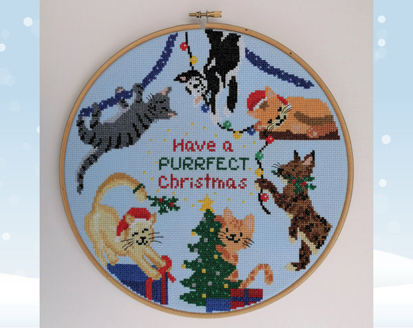 Christmas Cats cross stitch pattern. Six fun cartoon cats putting up Christmas decorations. Shown in hoop with plain background.