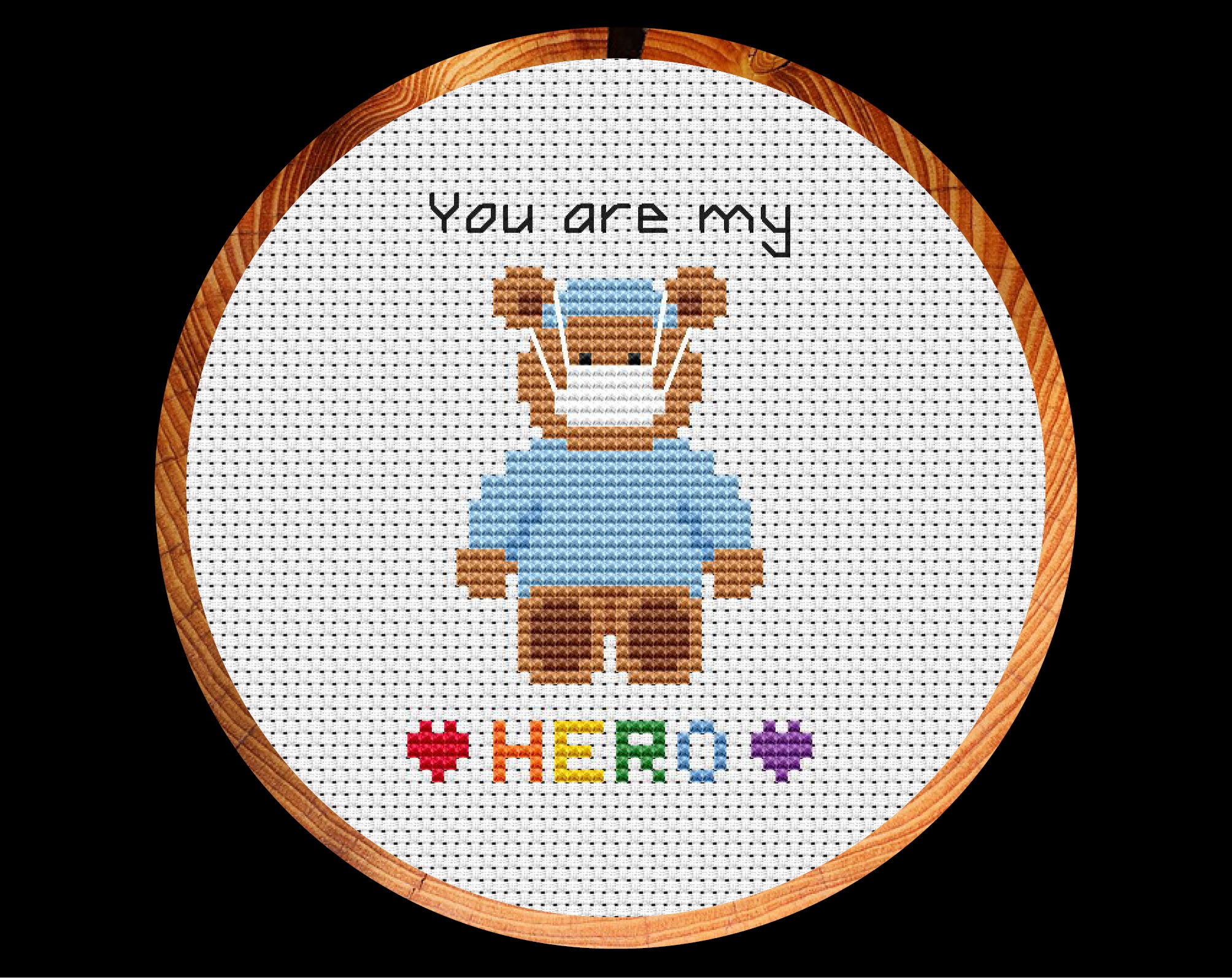 Cross stitch pattern of teddy bear wearing scrubs and a face mask, with the words 'You are my HERO'. Shown in hoop.