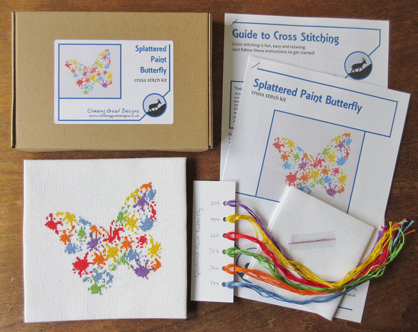 Splattered Paint Butterfly cross stitch kit - picture of contents: labelled box, guide to cross stitching, cross stitch chart, sorted DMC threads, fabric and needle.