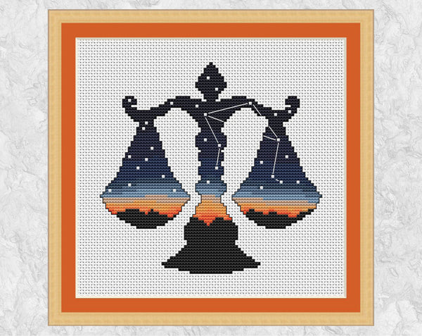 Cross stitch pattern of the silhouette of the weighing scales of Libra, filled with the last colours of the setting sun and with the constellation of Libra in the night sky. Shown with frame.