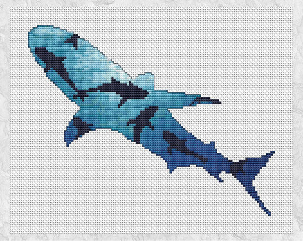 Cross stitch pattern of the silhouette of a shark, filled with a scene looking upwards through a shoal of sharks, with sunlight illuminating the water from above. Shown without frame.