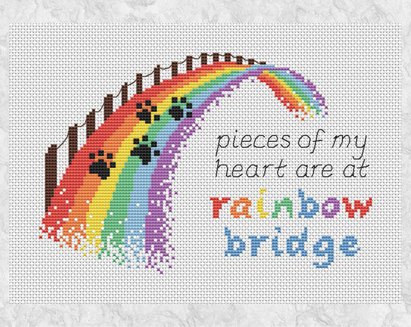 Cross stitch pattern of a rainbow bridge with the quote "pieces of my heart are at rainbow bridge". Shown without frame.