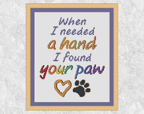 Cross stitch pattern of the words "When I needed a hand I found your paw", with a heart and paw print. Shown with frame.