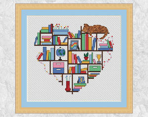 Cross stitch pattern of a heart shape made up of books, ornaments and a cat on bookshelves