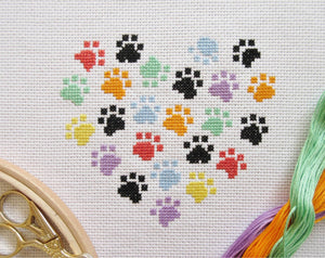 Cross stitch picture of a heart made up of rainbow and black coloured paw prints
