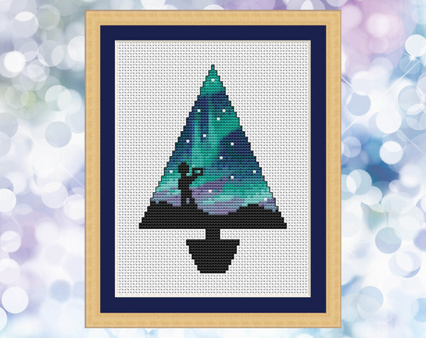 Aurora Christmas Tree cross stitch pattern. Image shows Christmas tree shape filled with aurora and silhouette of a photographer.