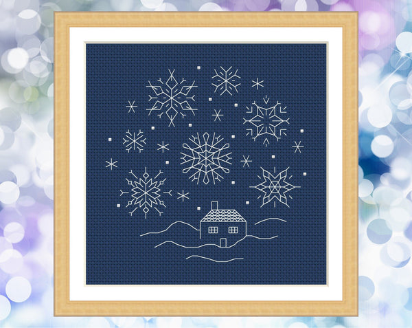 Blackwork Snow Scene cross stitch pattern. Six sided backstitched snowflakes falling on a small cottage. Shown in frame.