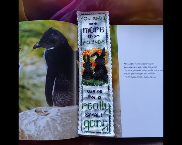Cross stitched bookmark with silhouette of two bunnies at sunset and the words 'You and I are more than friends  We're like a really small gang'. Bookmark is placed in a book.