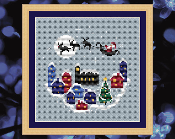 Christmas Village cross stitch pattern. Shown in frame.