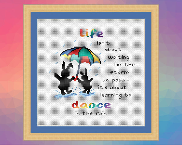 Dancing in the Rain cross stitch patterns. Two Together Bunnies with an umbrella and the words "life isn't about waiting for the storm to pass - it's about learning to dance in the rain". Shown in frame.