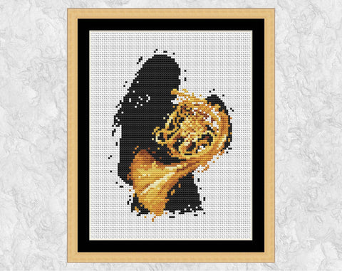 Female French Horn player cross stitch pattern. Shown in frame.