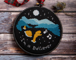 I'm a Believer cross stitch pattern. Fun image of Nessie in a loch singing "I'm a Believer". Stitched image in 6 inch hoop, photographed by Stacy Grant.