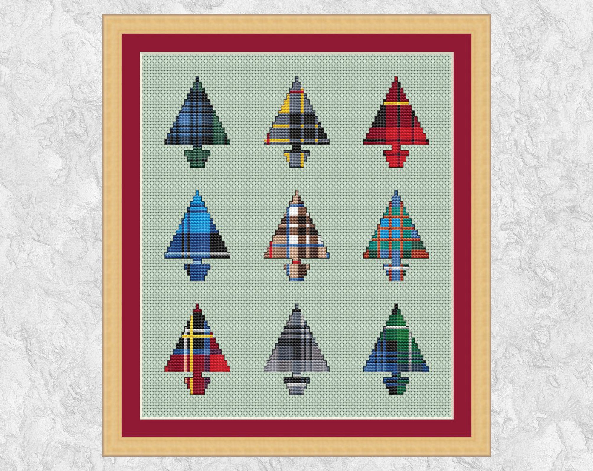 Nine Tartan Christmas Trees cross stitch pattern. Set of nine mini Christmas tree shapes filled with different Scottish tartan patterns. Shown with frame.