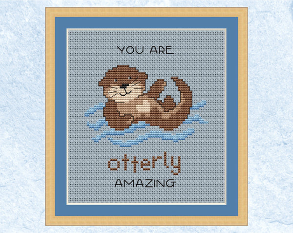 Otterly Amazing cross stitch pattern. Cartoon of an otter with the words "You are otterly amazing". Shown in frame.