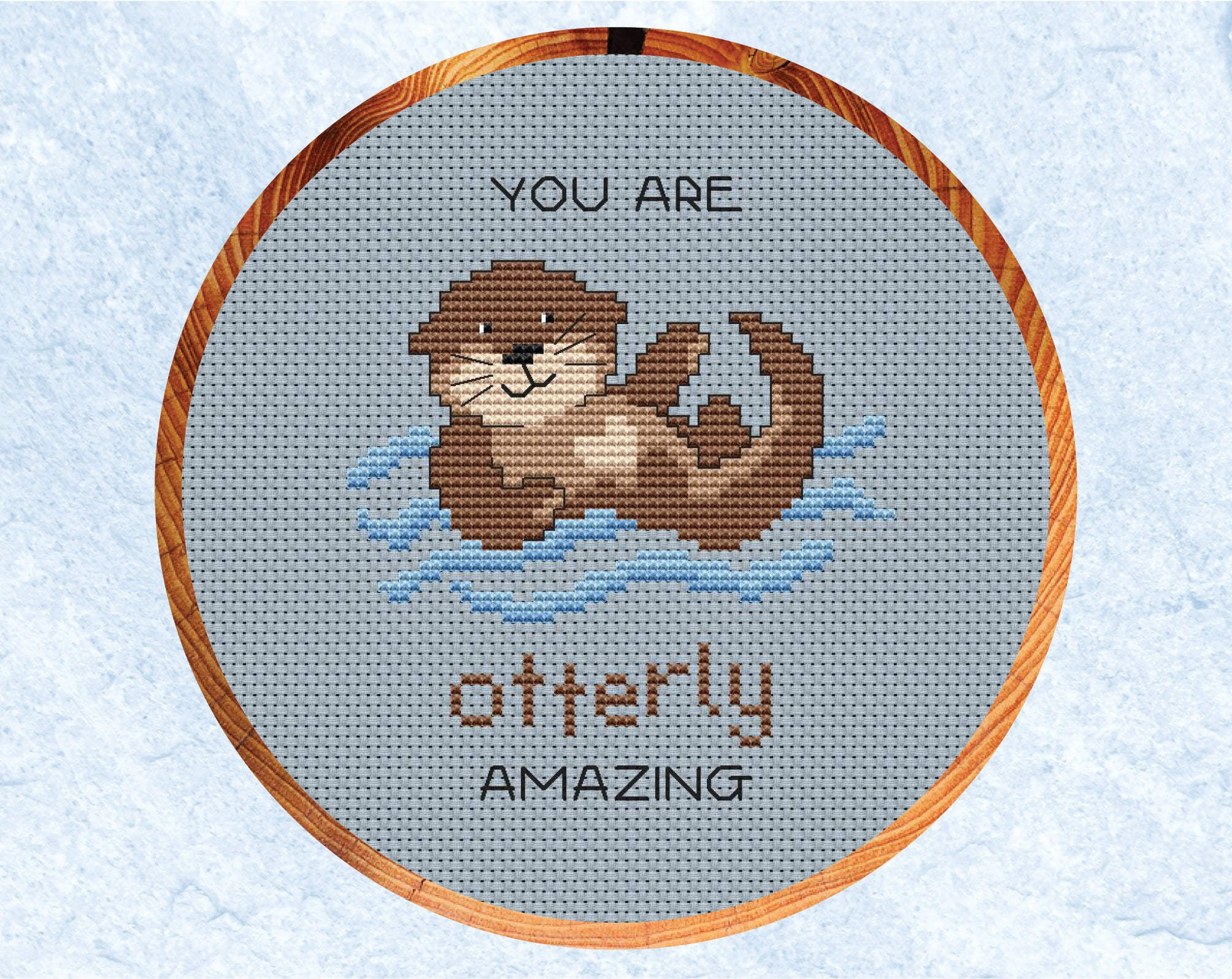 Otterly Amazing cross stitch pattern. Cartoon of an otter with the words "You are otterly amazing". Shown in six inch hoop.