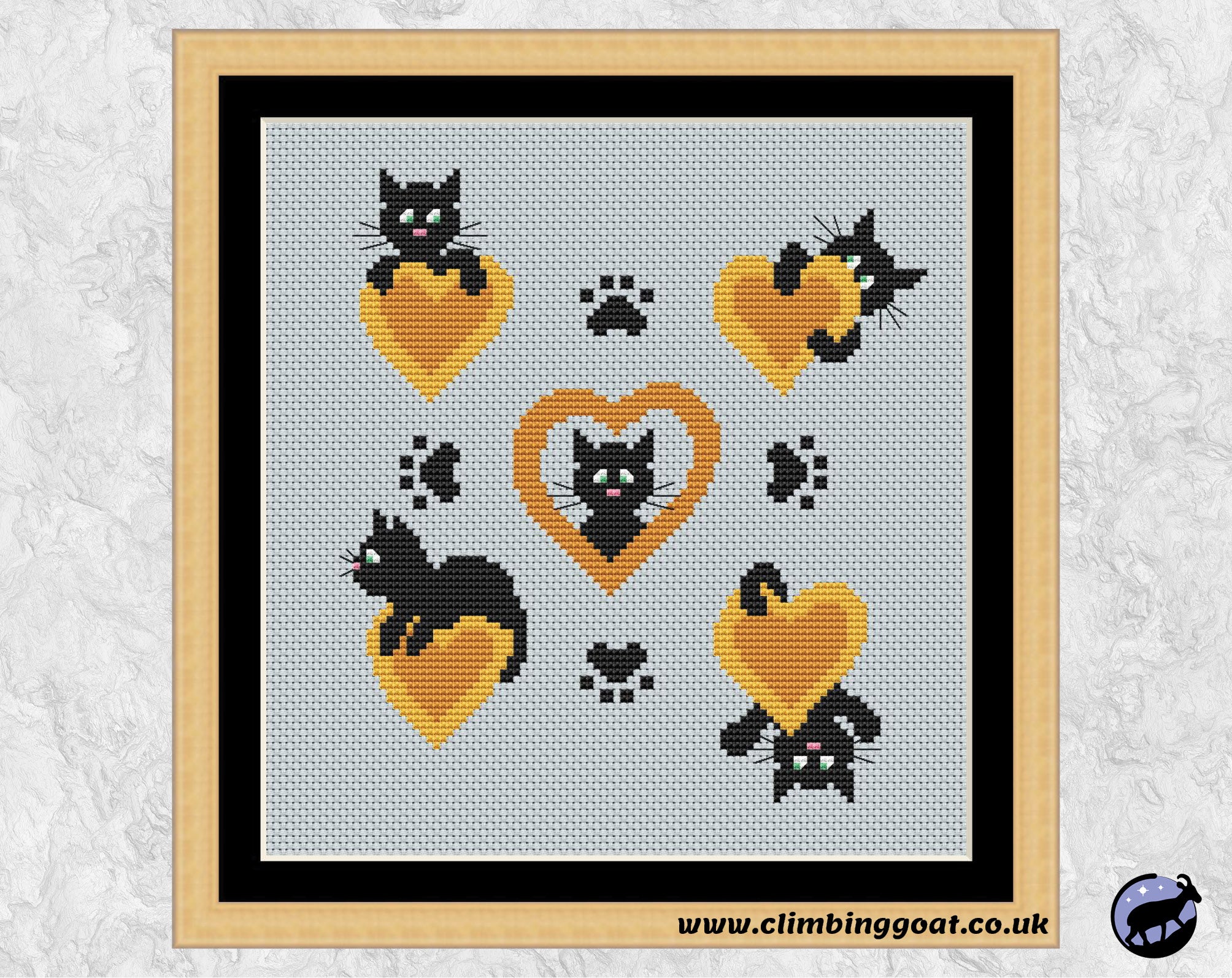 Peekaboo Cat Hearts cross stitch pattern. Cartoon cats peeking around golden hearts. Shown in frame.