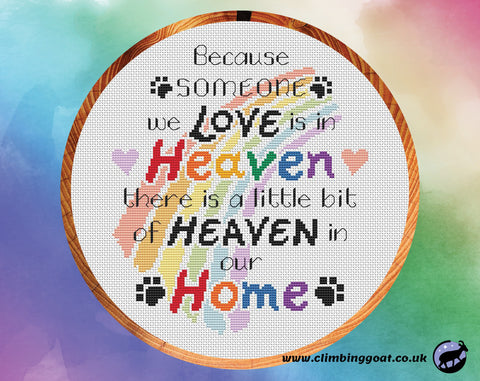 Pet memorial cross stitch pattern with the words "Because someone we love is in heaven, there is a little bit of heaven in our home" arranged over a pastel rainbow. Shown in hoop.