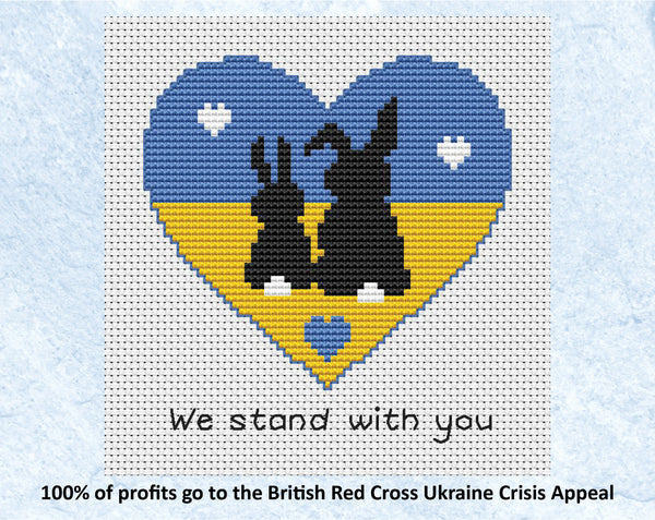"We Stand With You" cross stitch pattern of two bunny silhouettes in a heart shape filled with the colours of the Ukrainian flag. 100% of profits go to the British Red Cross Ukraine Crisis Appeal. Shown without frame.