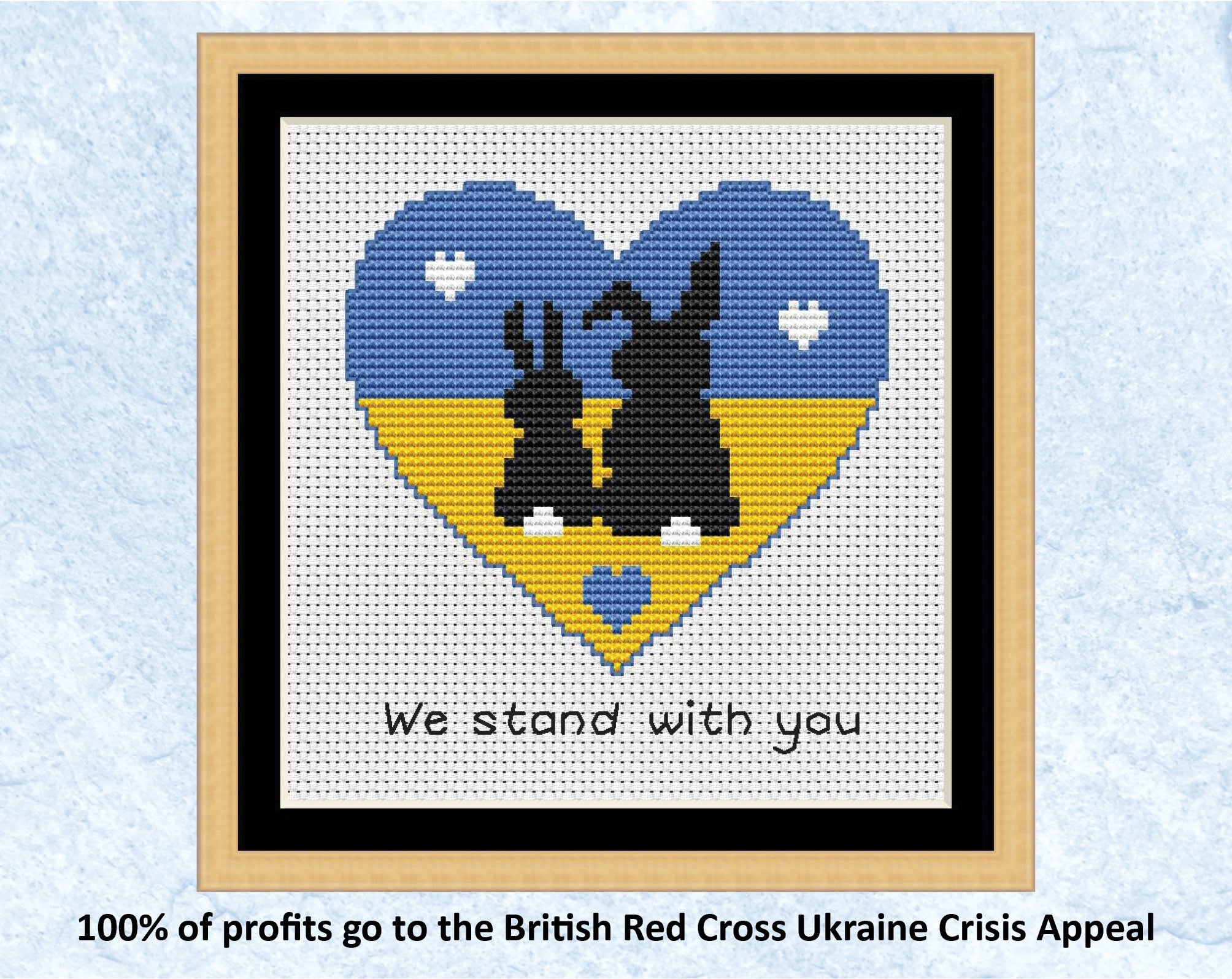 "We Stand With You" cross stitch pattern of two bunny silhouettes in a heart shape filled with the colours of the Ukrainian flag. 100% of profits go to the British Red Cross Ukraine Crisis Appeal. Shown with frame.