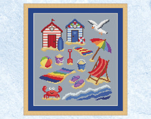 Beach Days cross stitch pattern - fun colourful design featuring beach huts, seagull, parasol, beach towels, spades, buckets, beach ball, deckchair, flipflops, crab, sand and waves. Shown with frame.