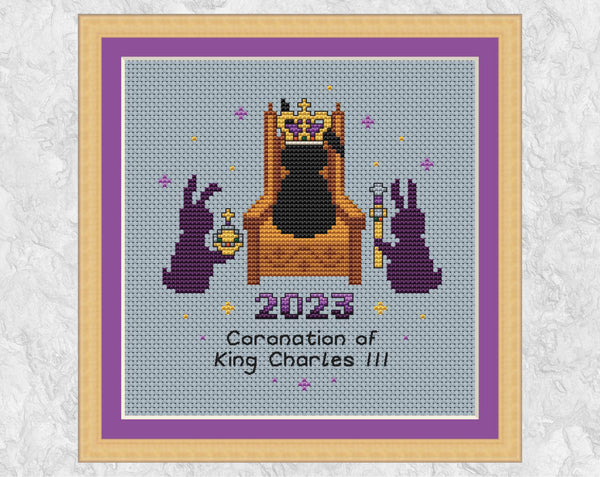 Coronation Bunnies cross stitch pattern. A bunny wearing a crown sits on a throne, with a bunny with an orb on one side and a bunny with a sceptre on the other. Shown in frame.