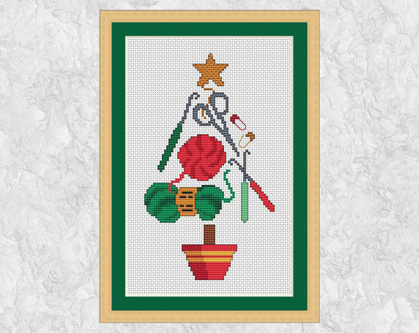 Crochet Christmas Tree cross stitch pattern. A Christmas Tree shape made up of yarn, scissors, crochet hooks and stitch markers - and ideal picture to cross stitch for any crochet lover. Shown with frame.