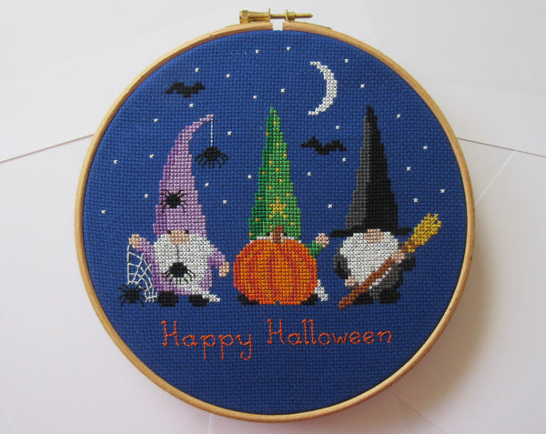 Halloween Gnomes cross stitch pattern. Three fun gnomes displayed in a hoop laid on paper.