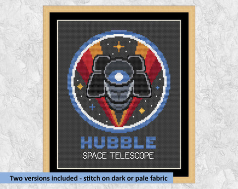 Hubble Space Telescope cross stitch pattern. Shown on black fabric in frame with the text 'Two versions included - stitch on dark or pale fabric'