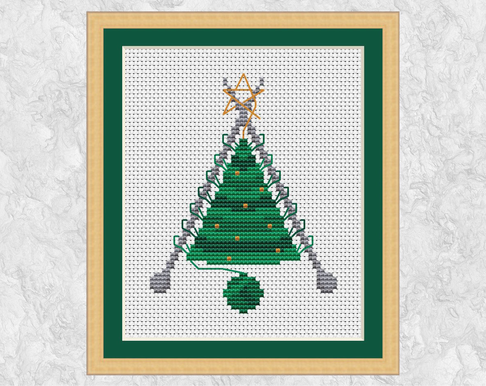 Knitted Christmas Tree cross stitch pattern. A knitted Christmas Tree shape still on the knitting needles, with a ball of yarn forming the pot. Shown with frame.