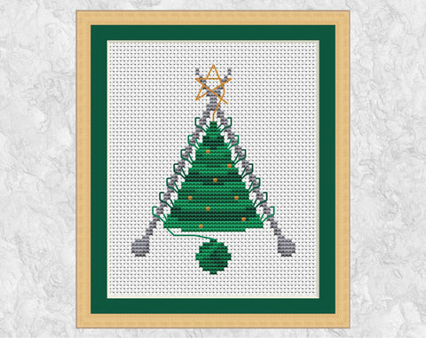 Knitted Christmas Tree cross stitch pattern. A knitted Christmas Tree shape still on the knitting needles, with a ball of yarn forming the pot. Shown with frame.