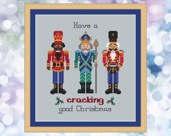Nutcracker cross stitch pattern. Three Nutcracker soldiers with the words 'Have a cracking good Christmas'. Shown in frame.