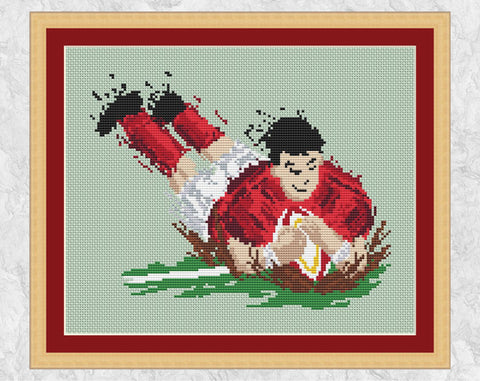 Splattered Paint Rugby Player cross stitch pattern. Design of a rugby player throwing himself over the touchline with the ball, scoring a try. Shown with frame.