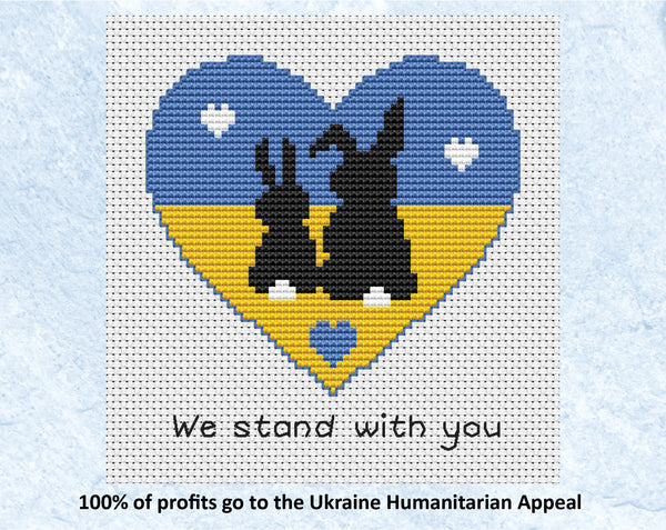"We Stand With You" cross stitch pattern of two bunnie silhouettes in a heart shape filled with the colours of the Ukrainian flag. 100% of profits go to the Ukraine Humanitarian Appeal. Shown without frame.