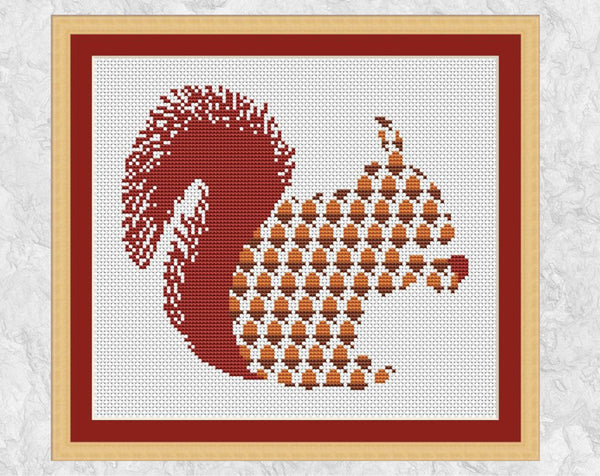 Silhouette cross stitch pattern of a red squirrel made up of acorns - and with one in its paws! Shown with frame.