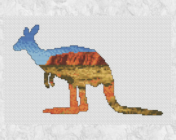 Cross stitch pattern of the silhouette of a Kangaroo filled with a view across the Australian outback to Uluru (Ayers Rock). Shown without frame.