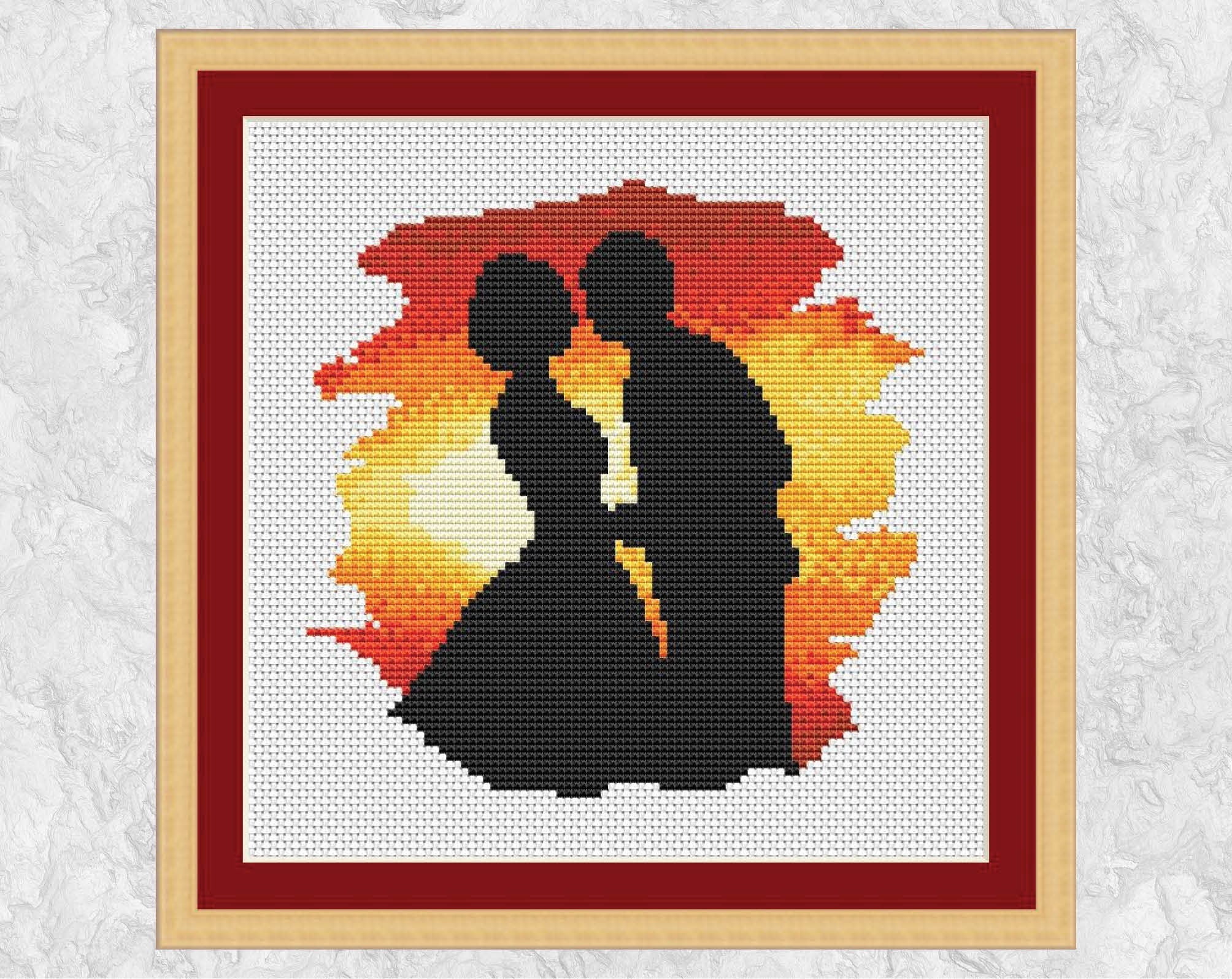 Wedding cross stitch pattern of the silhouette of a bride and groom about to kiss against the backdrop of a sunset. Shown with frame.