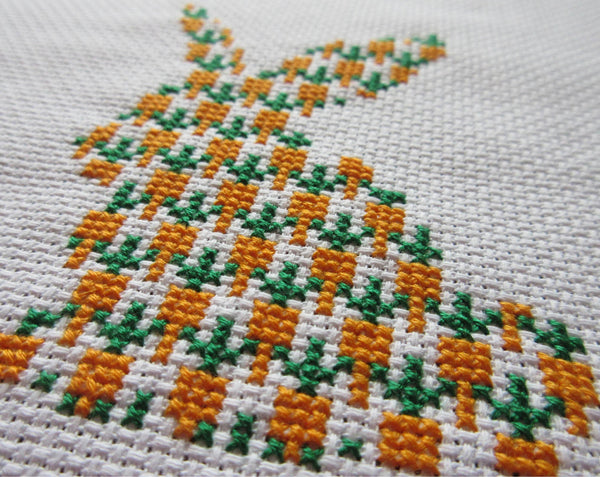 Carrot Bunny cross stitch kit - silhouette of a rabbit filled with carrots. Angled view of stitched piece.