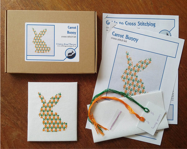 Carrot Bunny cross stitch kit - silhouette of a rabbit filled with carrots. Picture of what you will receive - labelled box, cross stitch instructions, full chart, sorted threads, fabric and needle. Picture also shows completed stitched piece.