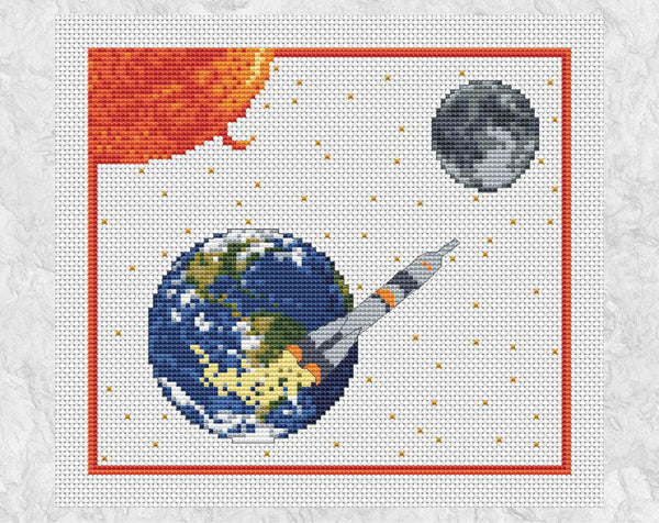 'To the Moon' - Space cross stitch pattern showing rocket, Earth, Sun and Moon. Shown on white fabric without frame.