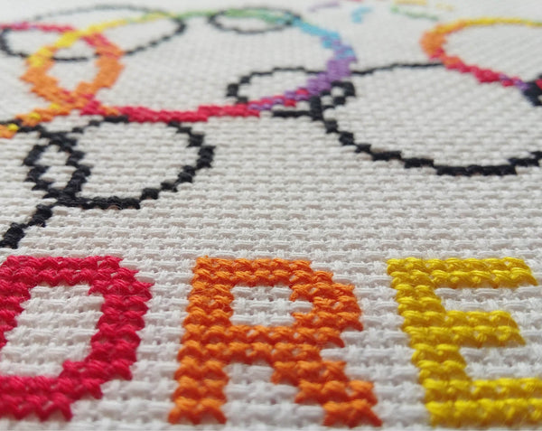 Cross stitch pattern of rainbow bubbles with the words Follow your DREAMS - close up of stitching