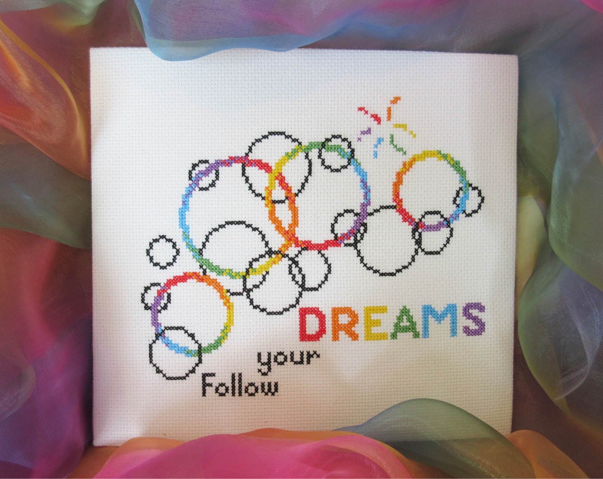 Cross stitch pattern of rainbow bubbles with the words Follow your DREAMS