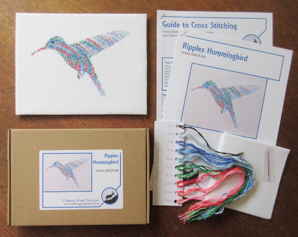 Ripples Hummingbird cross stitch kit - picture of kit contents: labelled box, completed cross stitch instructions, cross stitch pattern, sorted DMC threads, fabric and needle.