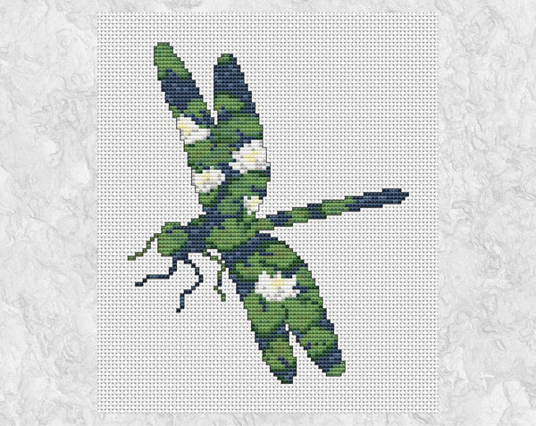 Cross stitch pattern of the silhouette of a dragonfly, filled with a peaceful scene of waterlilies on a pond. Shown without frame.