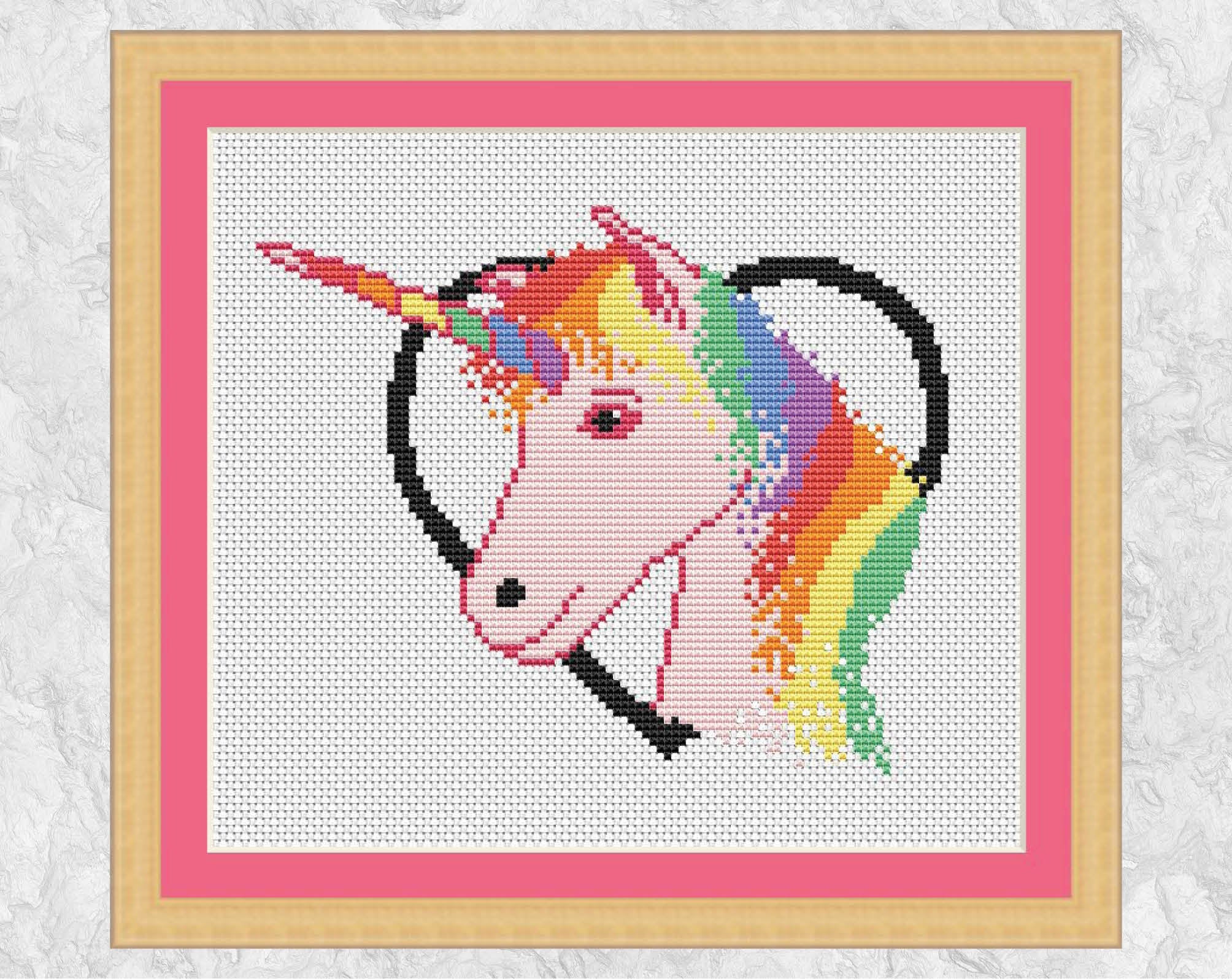 Cross stitch pattern PDF of a rainbow and pink unicorn framed in a heart. Shown with mount
