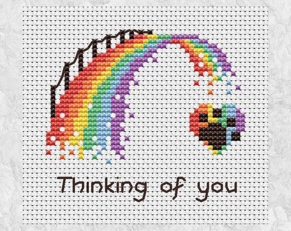 Cross stitch pattern PDF of a rainbow bridge ending at a paw print on a heart, with the words "Thinking of you". Shown without frame.