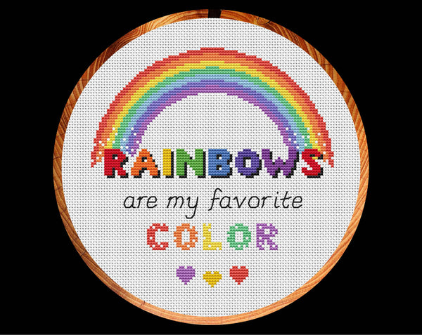 Cross stitch pattern of the quote 'Rainbows are my Favourite Colour' with a rainbow and hearts. US spelling version displayed in hoop.