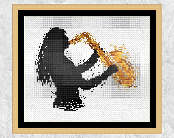 Cross stitch pattern of splattered paint female saxophone player. Shown with frame.